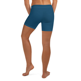 Teal blue athletic shorts worn by a female model, showcasing the form-fitting design and revealing the wearer's toned legs.