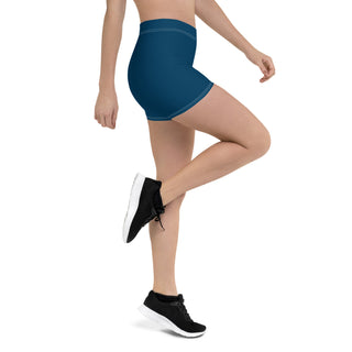 Navy blue athletic shorts with a sleek, fitted design showcased on a woman's legs. The shorts feature a solid color and a minimalist style, creating a stylish and sporty look. The model is wearing black athletic shoes, completing the activewear ensemble.