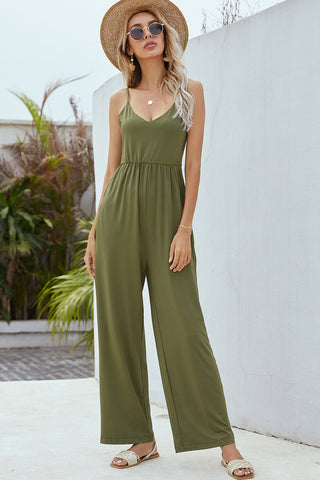 Chic olive green jumpsuit with wide legs, worn by a young woman outside with a straw hat and sunglasses, featuring a sleeveless design and a flattering cinched waist.