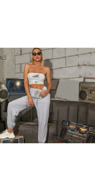 Versatile white pants for casual and trendy style, modeled by a fashionable woman against a wall backdrop with audio equipment.