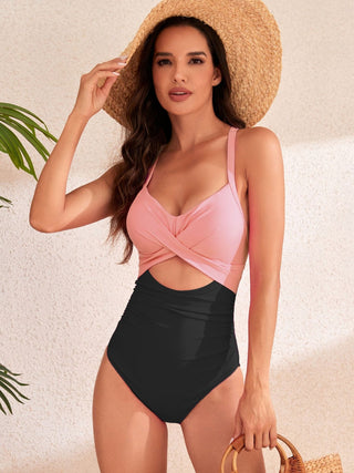 Stylish pink cutout swimsuit with waist tie, fashionable sun hat, and tropical accessory