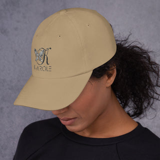 Beige cap with K-AROLE logo on front, worn by a person with dark curly hair against a grey background.