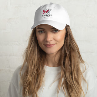 Stylish white K-AROLE branded dad hat with butterfly logo on a woman with long, wavy brown hair and a friendly expression.