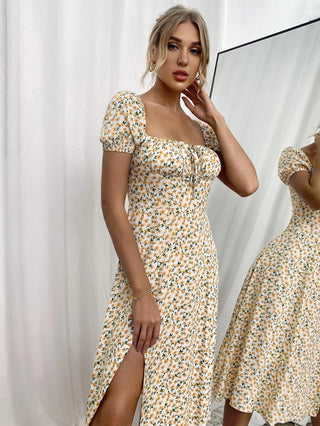 Elegant floral print dress with puff sleeves, fitted bodice, and flowing skirt with high slit. The model is posing against a white backdrop, showcasing the summer-inspired casual dress design.