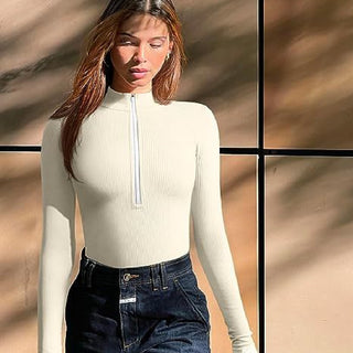 Elegant white ribbed long-sleeve top with zipped neckline modeled by a woman against a natural backdrop.