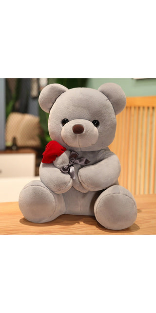 Soft gray plush teddy bear with a red scarf, sitting on a wooden surface in a cozy home setting.