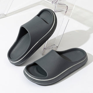 Sleek, modern men's slip-on sandals in a dark, neutral color. The minimalist design and textured sole provide both style and comfort for indoor or casual outdoor wear.