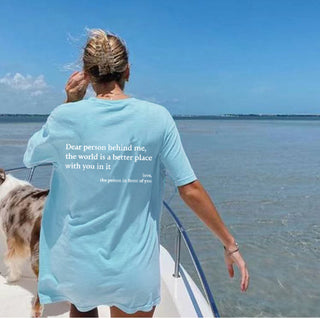 Person on a boat wearing a teal T-shirt with a message "Dear person behind me, the world is a better place with you in it"