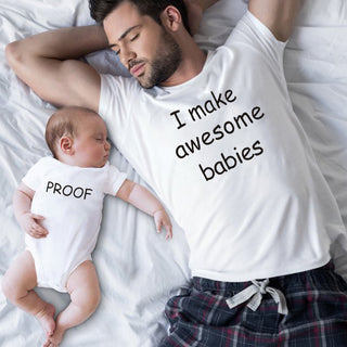 Matching parent and child t-shirts in white with text, "I make awesome babies" and "Proof", worn by a sleeping father and baby on a bed.