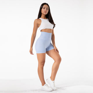 Comfortable high-waist seamless yoga shorts with a white crop top, worn by a young woman with long dark hair against a plain white background.