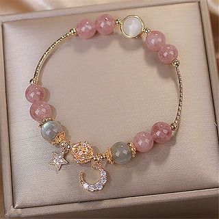 Natural Stone Star And Moon Strawberry Crystal Bracelet for Women, featuring elegant rose quartz beads, gold-tone charms, and sparkling accents displayed in a jewelry box.