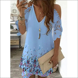 Elegant blue floral dress with cold-shoulder design and intricate embroidered detailing, accessorized with boho-chic jewelry and a stylish clutch.