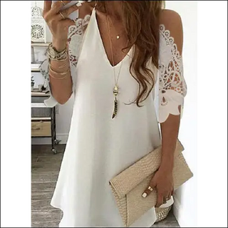 Elegant white lace-trimmed dress with long wavy hair, accessories, and clutch bag displayed on a wooden background.