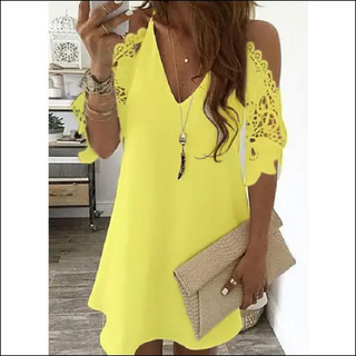 Vibrant yellow cold shoulder dress with lace detailing, worn by a woman standing in a kitchen.