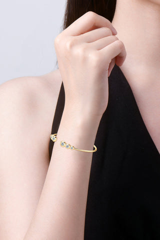 Elegant diamond cuff bracelet with 18K gold-plated sparkly cubic zirconia stones, showcased on a woman's arm against a dark background.