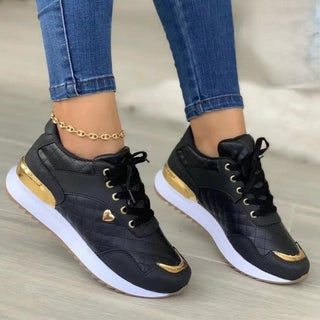 Stylish black and white patchwork sneakers with gold accents and lace-up closure, worn with cuffed blue jeans.