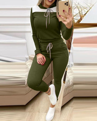 Stylish olive green activewear set featuring a hooded top and matching jogger pants, captured in a trendy home interior setting.