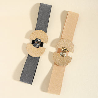 Decorative fashion belts with glittering pearl and buckle accents against a plain beige background.