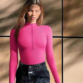 Stylish pink long-sleeved bodysuit for women, featuring a ribbed texture and a high neckline, captured in a modern and trendy setting.