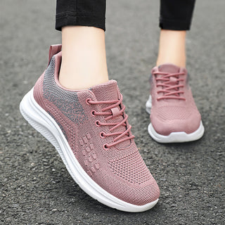 Light and breathable pink knit sneakers with lace-up design, worn by a person with black pants, providing a stylish and comfortable footwear option.