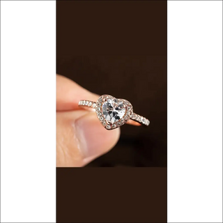 Fashion crystal heart-shaped wedding rings for women. Rose gold ladies engagement jewelry with sparkling crystals displayed on a dark background.