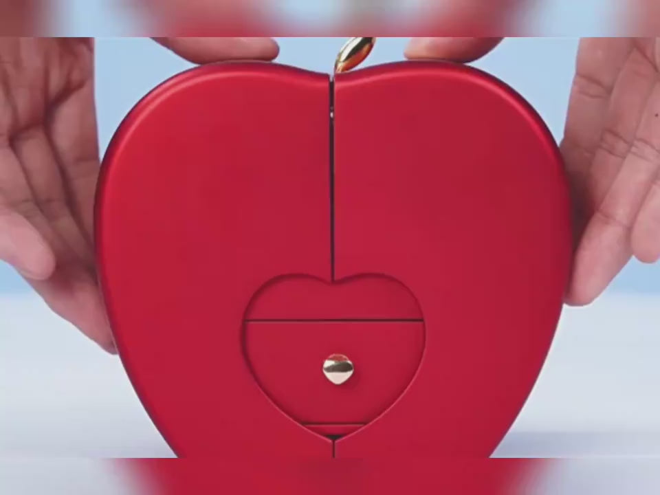 Vibrant red heart-shaped jewellery box held in hands, featuring intricate detailing and a metallic latch, showcasing an elegant and romantic design.