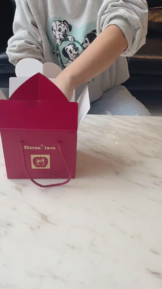 Elegant red gift bag from K-AROLE's women's fashion collection on a marble surface, showcasing the brand's stylish and thoughtful products.