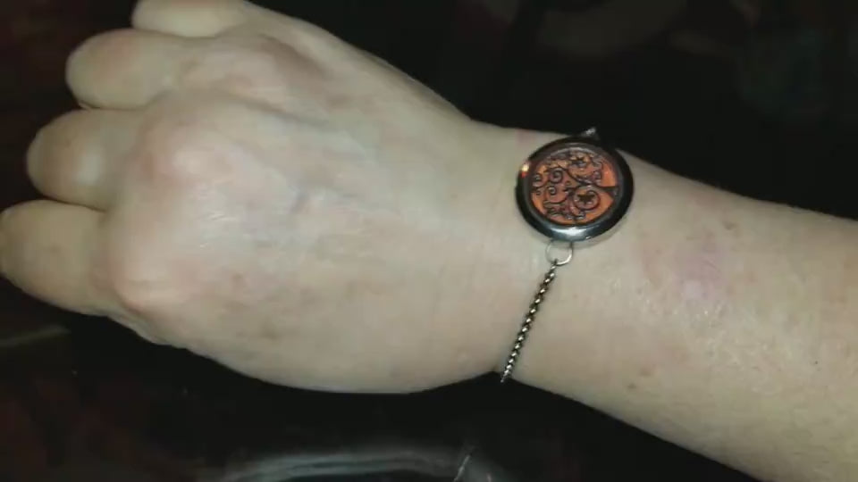 Elegant stainless steel aromatherapy bracelet with adjustable metal chain and intricate floral motif on a dark, minimalist background.