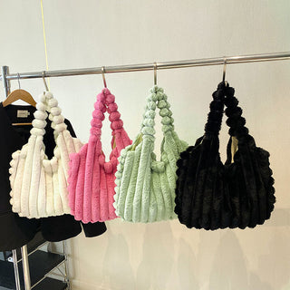 Colorful, textured handbags hanging on a clothing rack