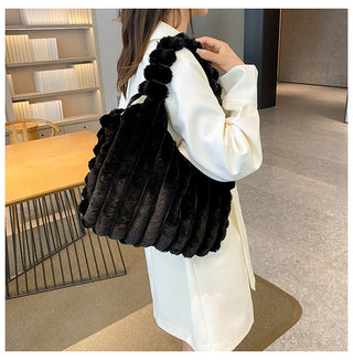 Luxurious black and white faux fur plush bag with pom-pom details, held by a woman in a stylish winter outfit, showcasing a fashionable and cozy accessory.