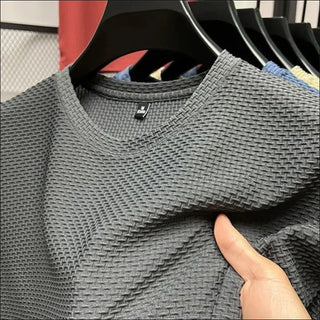 Gray mesh textured short sleeve t-shirt from the K-AROLE apparel brand, displayed on a clothing rack.