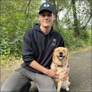 Smiling young man with a dog on wooded path