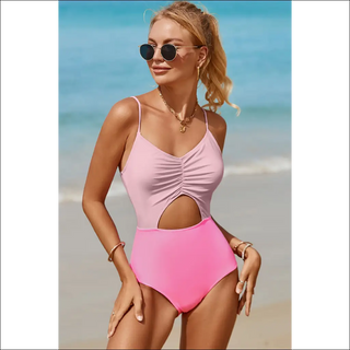 Stylish beach attire: Pink one-piece swimwear with cutout detailing, spaghetti straps, and fashionable sunglasses against the backdrop of a tranquil ocean.