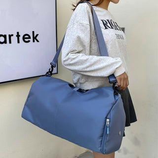 Women's blue sports/travel bag with dry and wet separation compartments and large storage capacity, displayed alongside a gray background with the Artek logo.