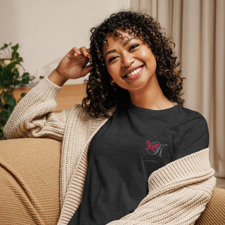 Smiling woman wearing a relaxed black t-shirt with a design, sitting on a couch surrounded by home decor.