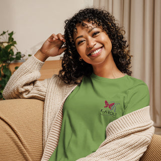 Smiling woman in green K-AROLE branded t-shirt and cozy neutral cardigan, seated against an interior background.