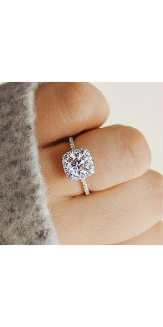 Elegant crystal heart-shaped engagement ring on woman's finger, showcasing a sparkling diamond centerpiece surrounded by a delicate halo setting, in a classic and timeless design.