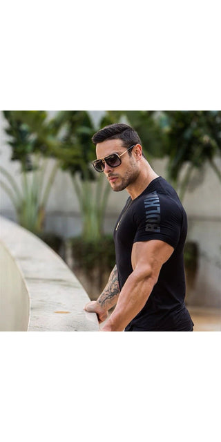 Stylish muscular male model in black t-shirt and sunglasses posing outdoors