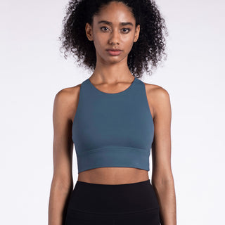Supportive women's grey sports bra with racerback design from K-AROLE's fitness apparel collection, showcased on a model with curly hair against a plain background.