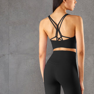 Sleek black yoga bra with criss-cross back straps, paired with matching leggings, showcased against a minimalist gray background.