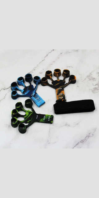 Diverse finger resistance exercisers on marble surface. Finger strengthening equipment with varying resistance levels for physical therapy and recovery.