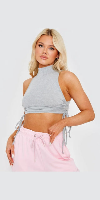 Stylish and trendy grey cropped top with side tie detail worn by a young blonde female model against a plain white background.