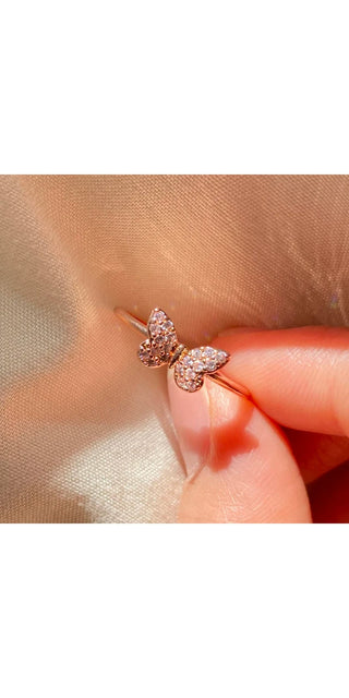 Elegant rose gold crystal butterfly ring on human hand, sparkling wedding jewelry accessory for women's fashion.