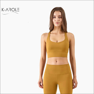 Stylish sports bra with cross back design, showcasing a model wearing the mustard-colored activewear piece by K-AROLE fashion brand.