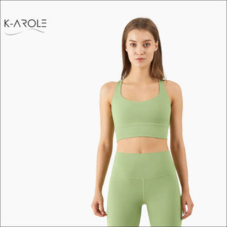 Woman wearing a light green cross-back sports push-up yoga bra from the K-AROLE brand, in a white background.
