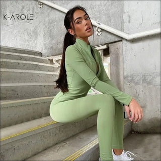 Sleek green fitted leggings and jacket set from K-AROLE, the trendy women's fashion brand. The model poses confidently on a concrete staircase, showcasing the comfortable, versatile activewear.