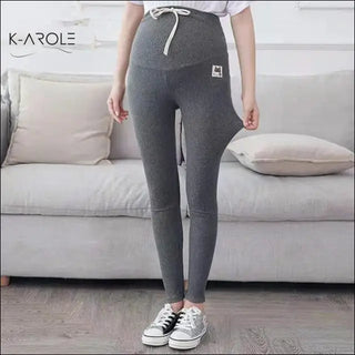 Stylish maternity leggings from K-AROLE, featuring a comfortable knit fabric and a drawstring waistband for a customized fit. The leggings are designed to flatter and support the wearer during pregnancy.