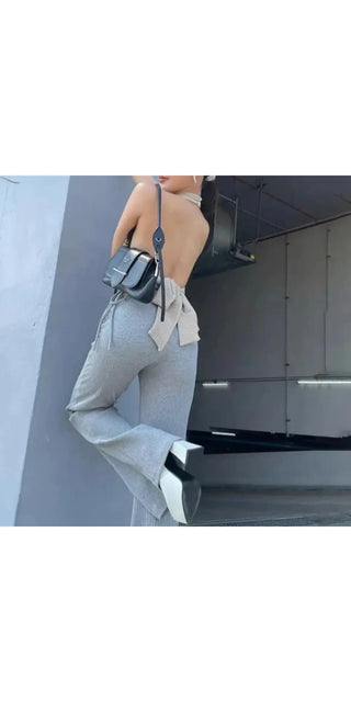 Slim fit gray bottoms with a minimalist, modern design, complementing the model's casual yet stylish look against a plain backdrop.