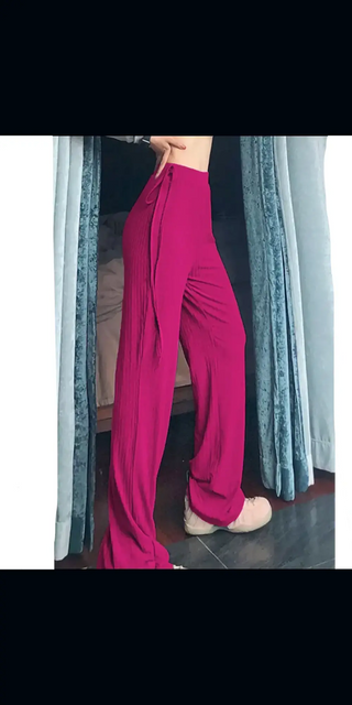 Slim-fit fuchsia pink palazzo pants with high waist, showcased against a gray curtain backdrop.