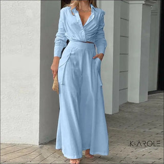 Elegant light blue long dress with pockets, showcased by a professional model in a store setting. The stylish outfit from the K-AROLE fashion brand features a chic, comfortable design that can be dressed up or down for various occasions.